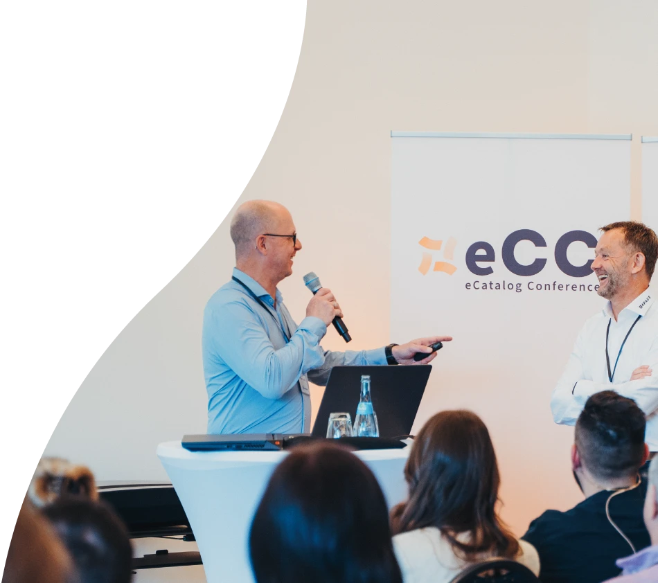 Herby Tessadri, Vertriebsleiter von crossbase, spricht mit Mikrofon in der Hand vor Publikum. Er weist mit der linken Hand auf Achim Angel von 4PACE, der gemeinsam mit ihm einen Vortrag hält. Beide lachen und schauen sich direkt an.