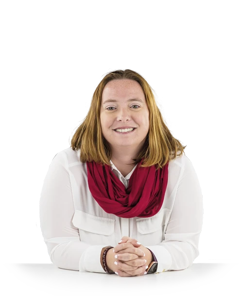 Stefanie Löwe stands behind a table wearing a white blouse. She leans on her forearms and smiles at the camera.
