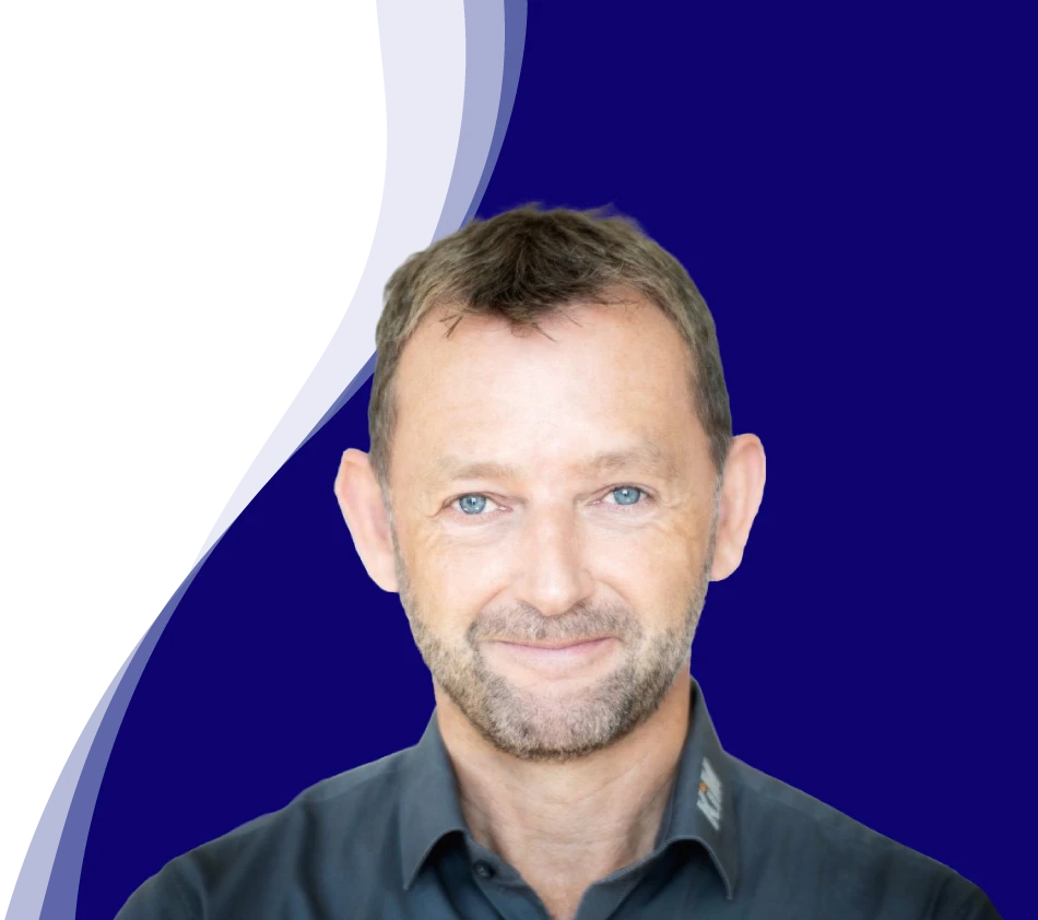 Achim Angel, Managing Director of KiM GmbH - Member of 4PACE, smiles friendly into the camera. He has short brown hair, a short beard and is wearing a dark gray shirt with a slightly open collar. A curved wave shape in white, light blue and dark blue can be seen in the background, giving the picture a modern design.