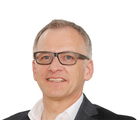 Wolfgang Maier, directeur marketing chez LEUCO, regarde aimablement la caméra. Il porte des lunettes noires marquées, une chemise blanche à col ouvert et une veste sombre. Ses cheveux courts sont grisonnants.