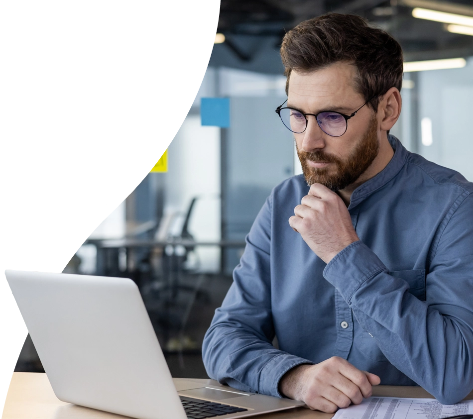 Un homme réfléchit sur son ordinateur portable pour savoir s'il doit choisir le système PIM en cloud ou sur site.