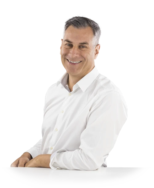 Jochen Muffler, en chemise blanche, est appuyé contre une table et regarde la caméra en souriant.